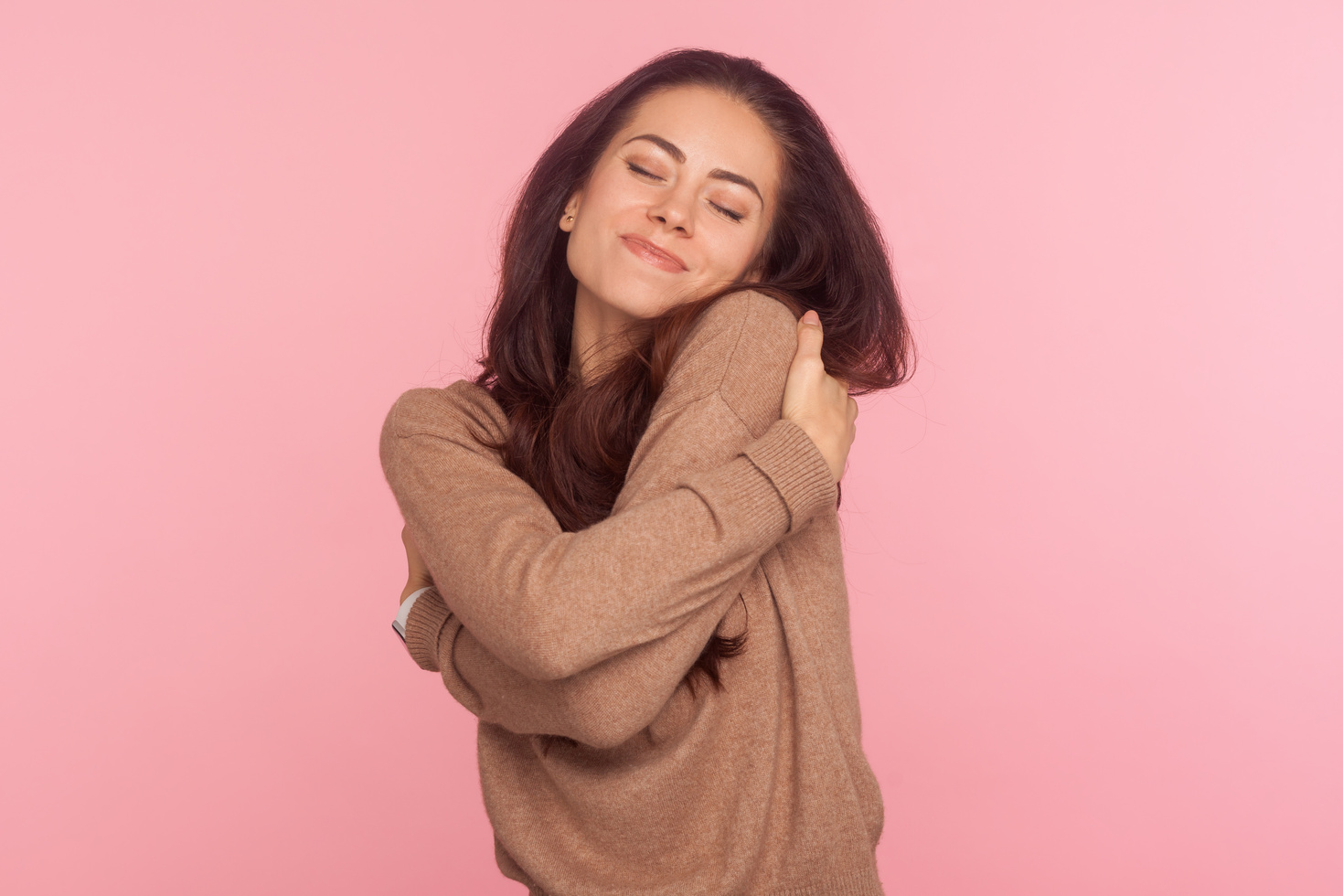 Young Woman Hugging Herself  on Pink Background